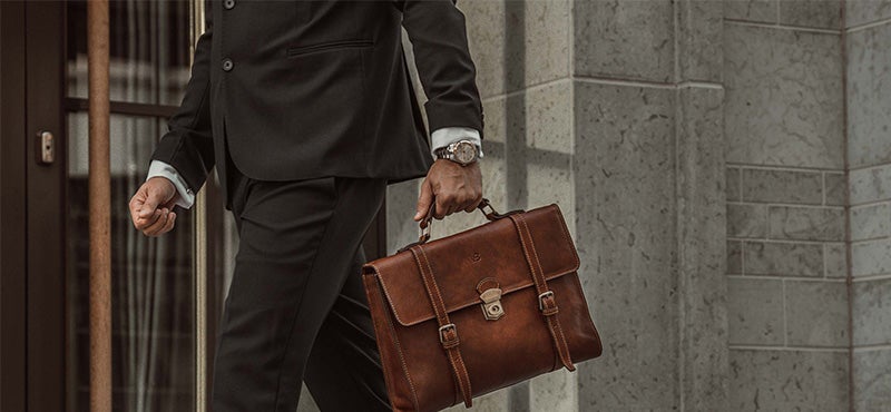 man wearing suit carrying brown leather briefcase
