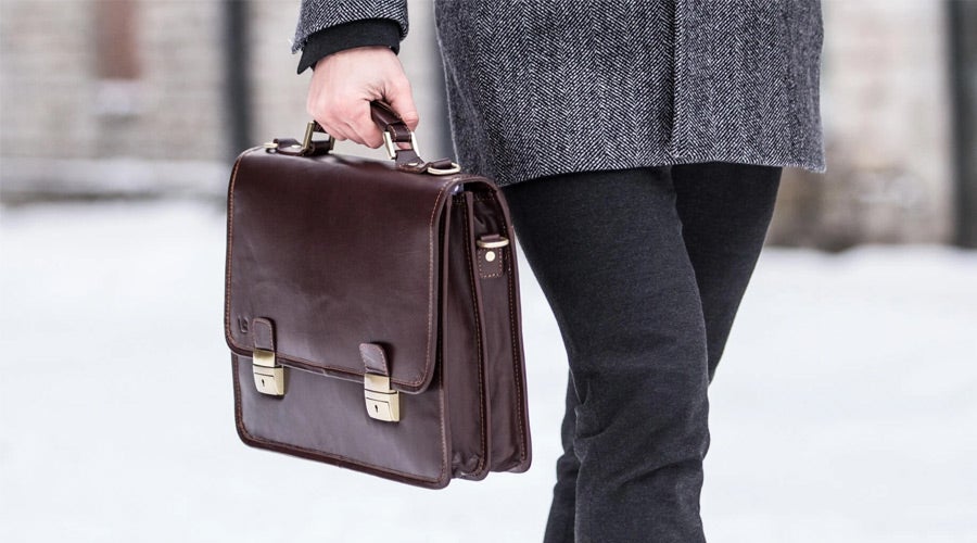brown leather briefcase held by man outside