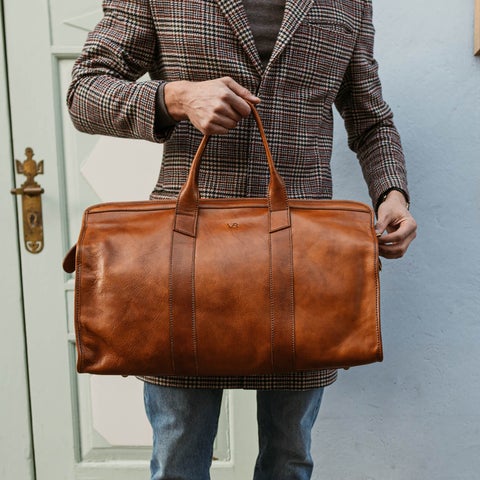 man in suit holding cognac JUNYUAN weekender bag