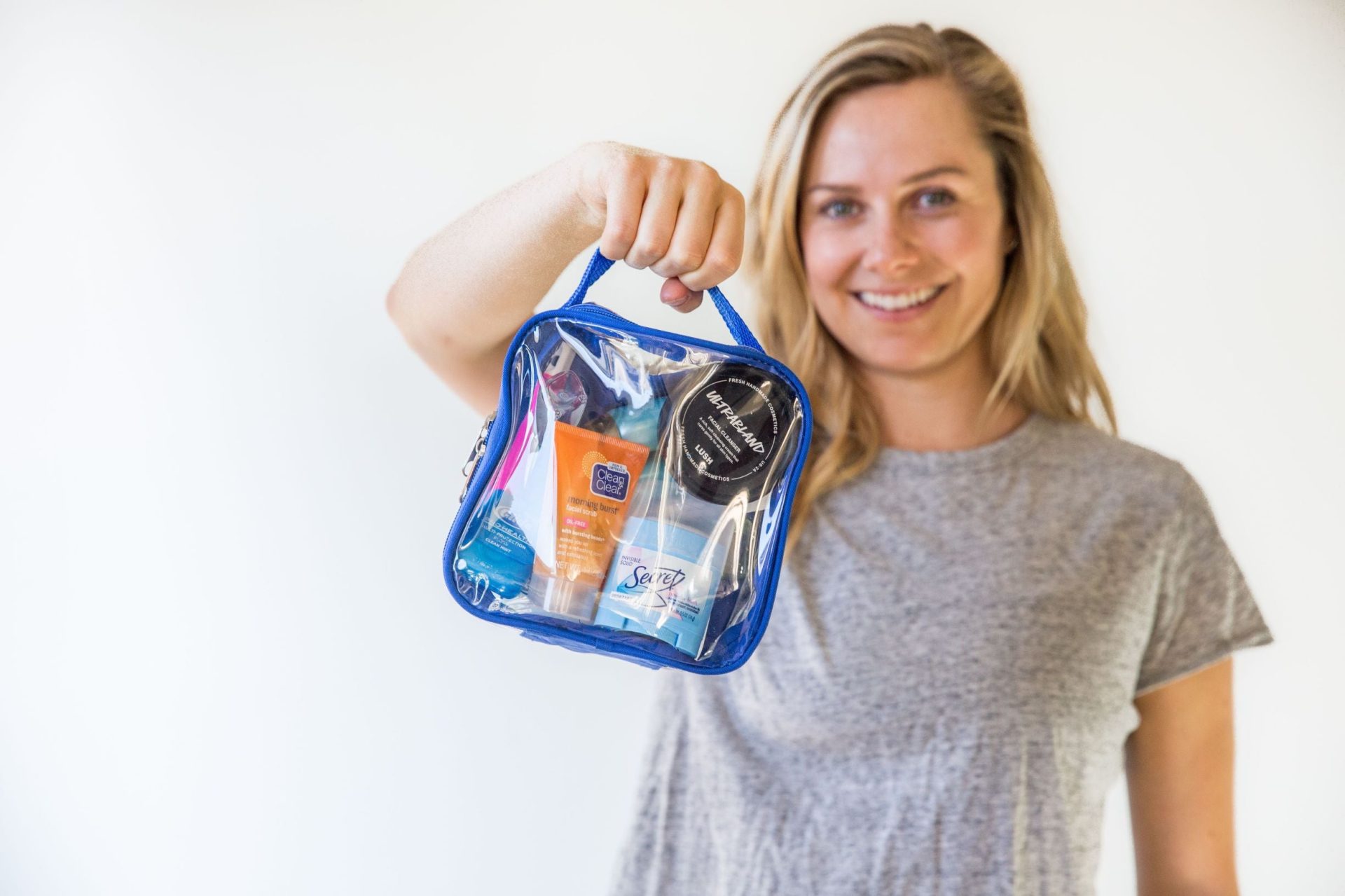 Tali holding a royal blue quart size bag packed with toiletries