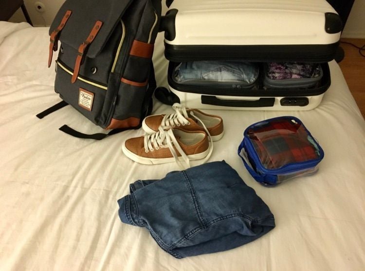 Shoes, backpack, carryon suitcase and other travel items on the bed