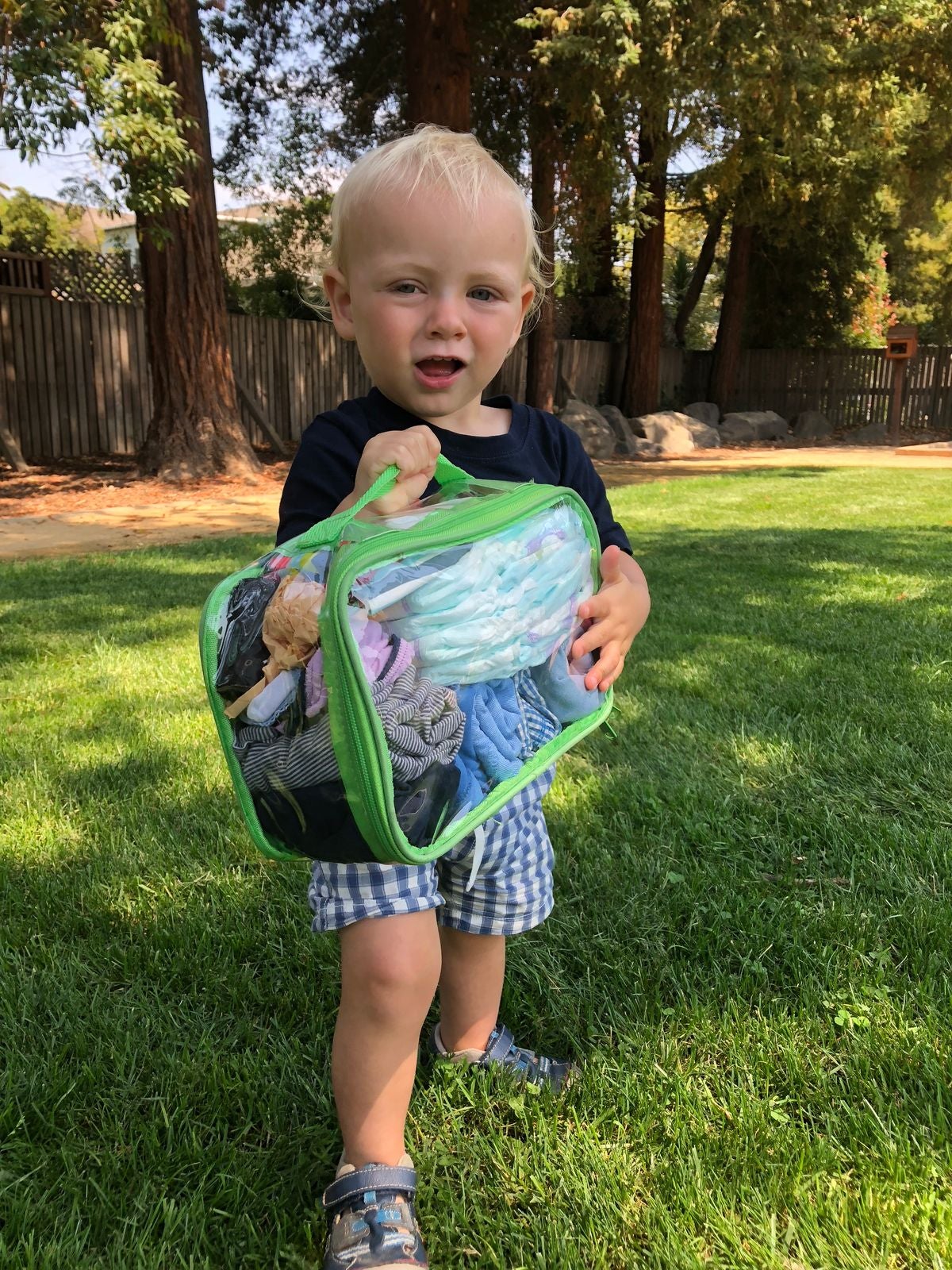 baby holding a green small cube with travel essentials