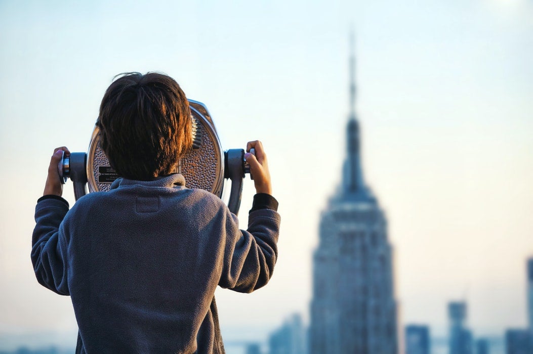 Kid looking through binoculars in Top of the Rock, New York