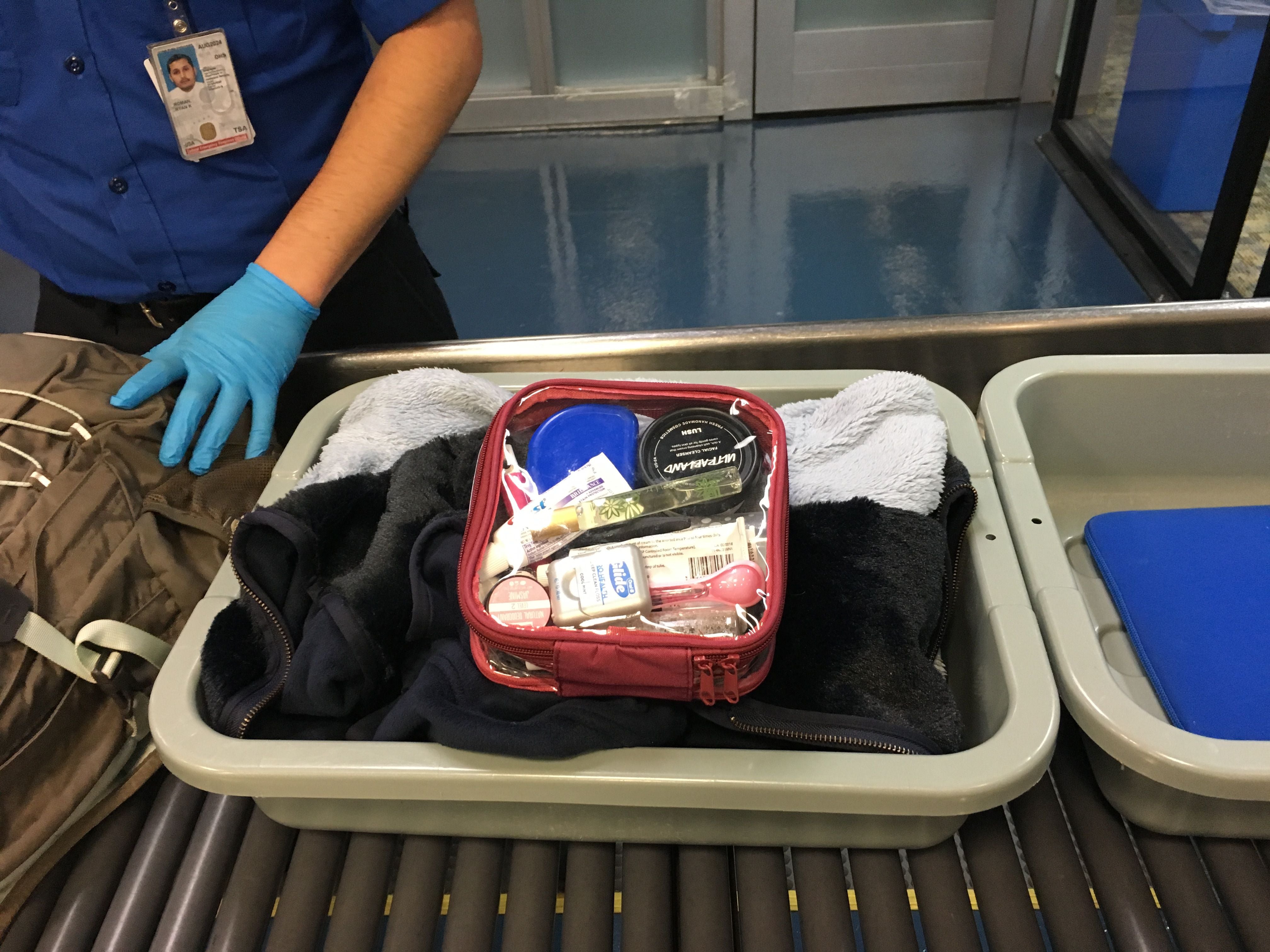 Travel items and small packing cube on a tray passing through airport security
