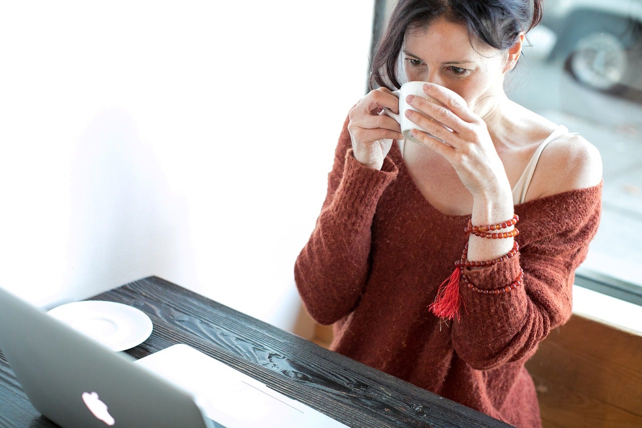 Woman drinking coffee while buying packing cells online