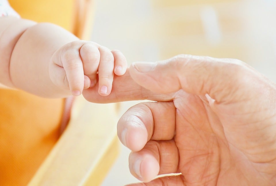 Lap infant holding on to parent’s finger during flight