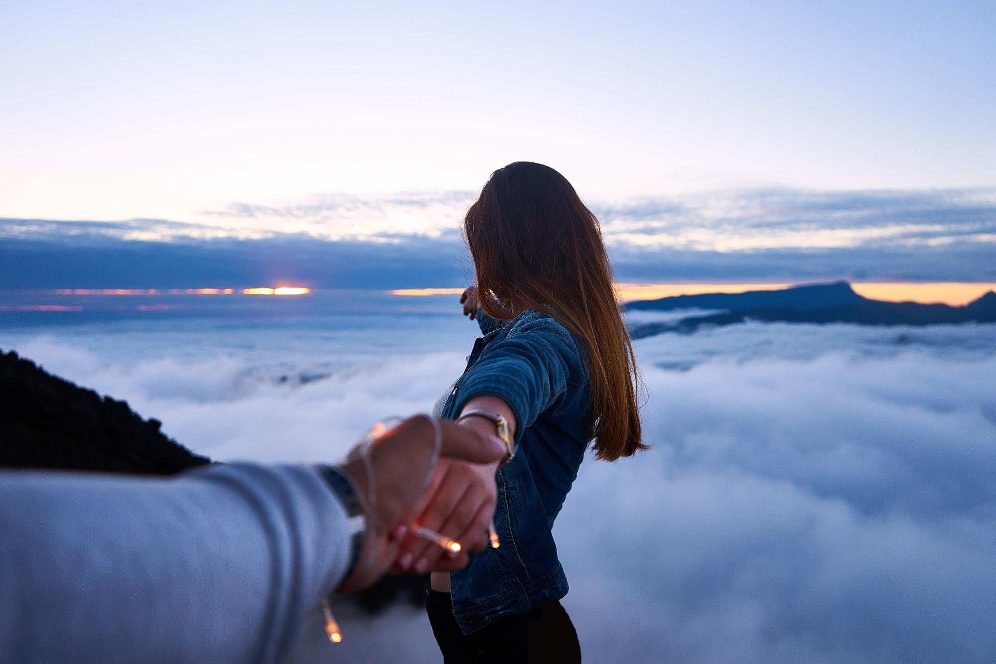 Romantic setup in clouds and fairy lights with a girl holding hands with partner