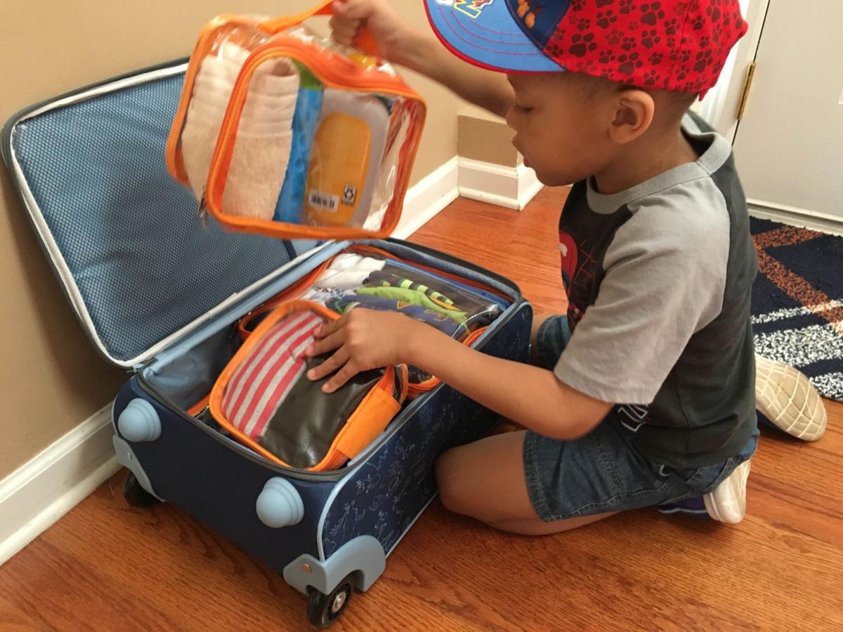 little boy and his packed suitcase with packing cubes