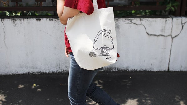woman carrying canvas tote bag screen printed with camera