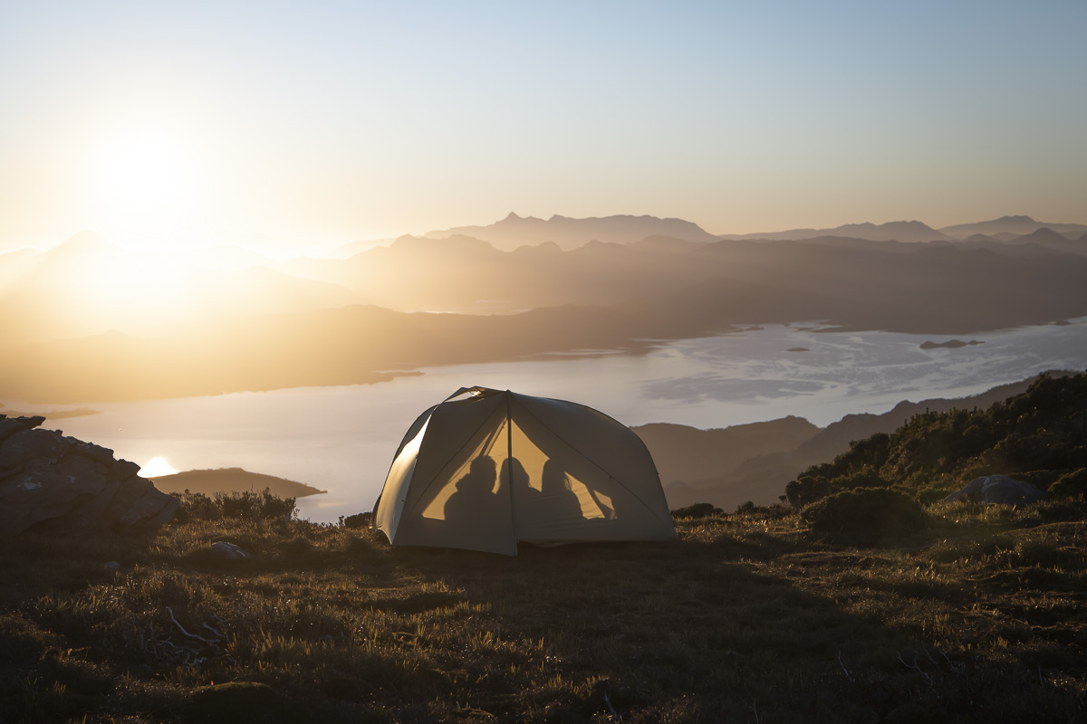 Silhouette of three people in spacious Telos tent with mountain view