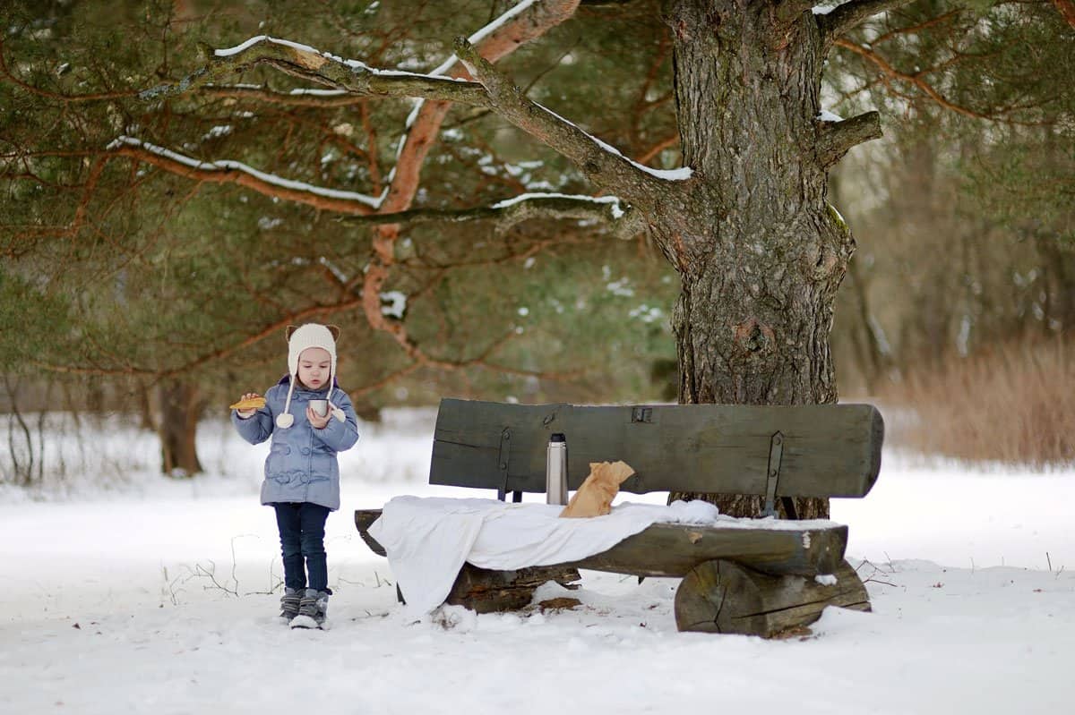 Young girl having a picnic lunch in the snow. 