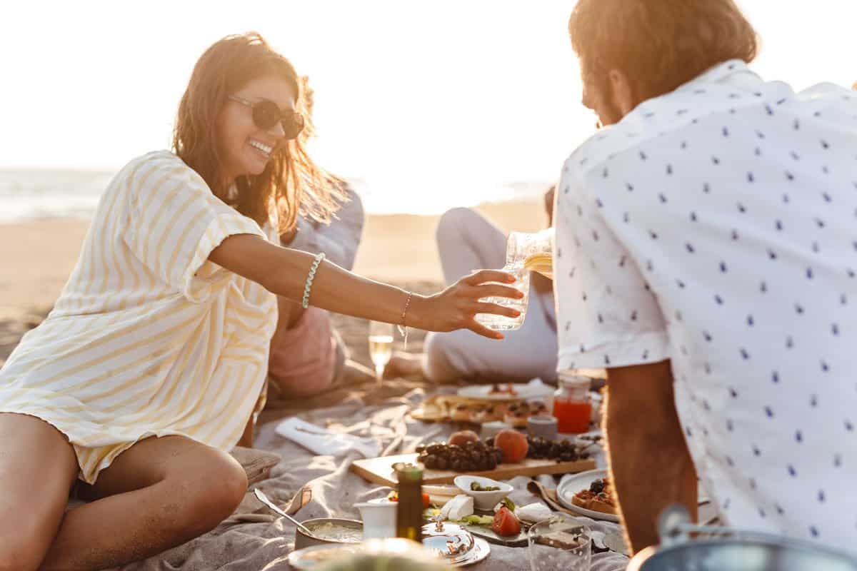 Young couple enjoying a beach picnic with a group of friends. 