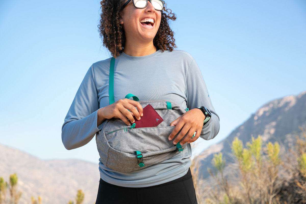 Woman on a hike, pulling an Allett nylon Sport Wallet from her shoulder pack