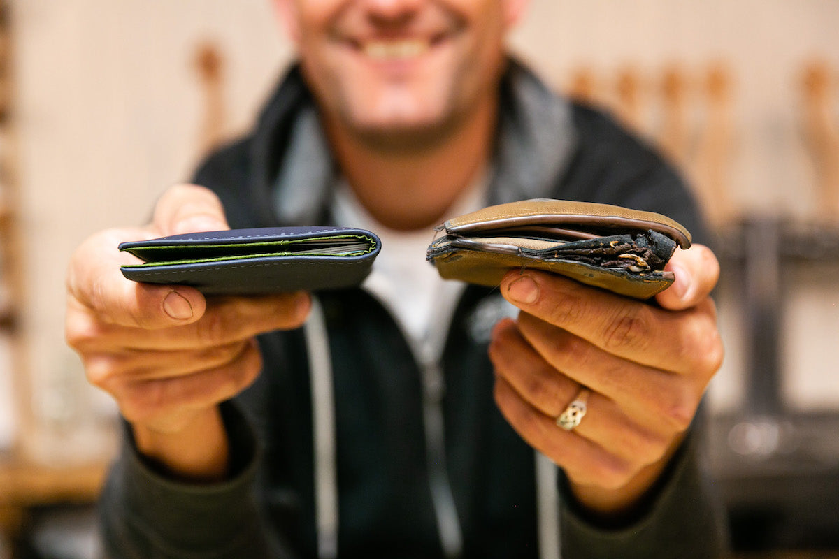 Man holding an Allett leather slim wallet in one hand and a basic leather wallet in the other showing a side-by-side comparison of how much slimmer the Allett wallet is.