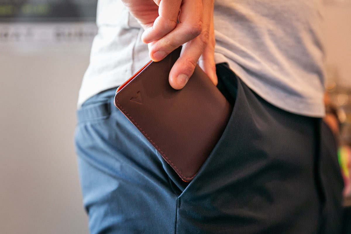 Close up side shot of man pulling an Allett leather hybrid card wallet out of his front pocket.