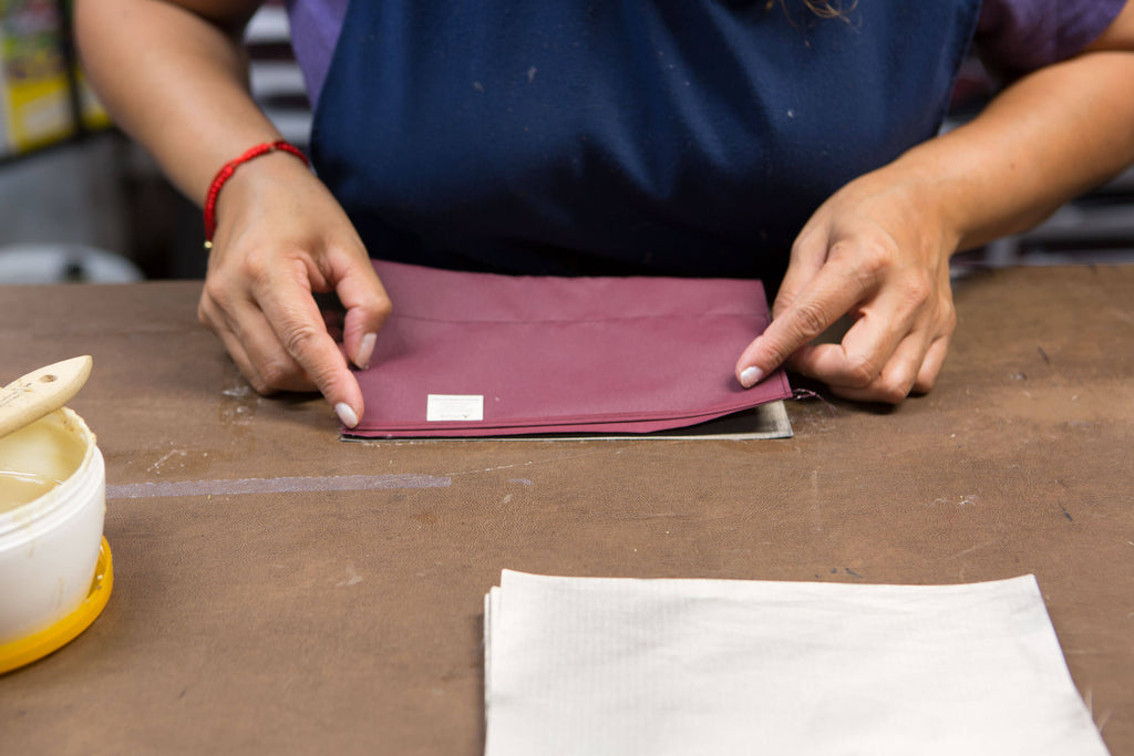 skilled worker putting final touches on assembly of Burgundy wallet