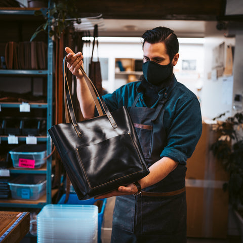Man holding black leather tote bag