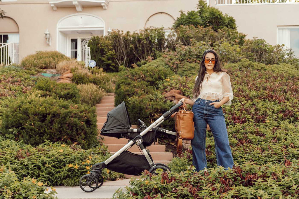 Stylish mom pushing a stroller with a faux leather diaper bag