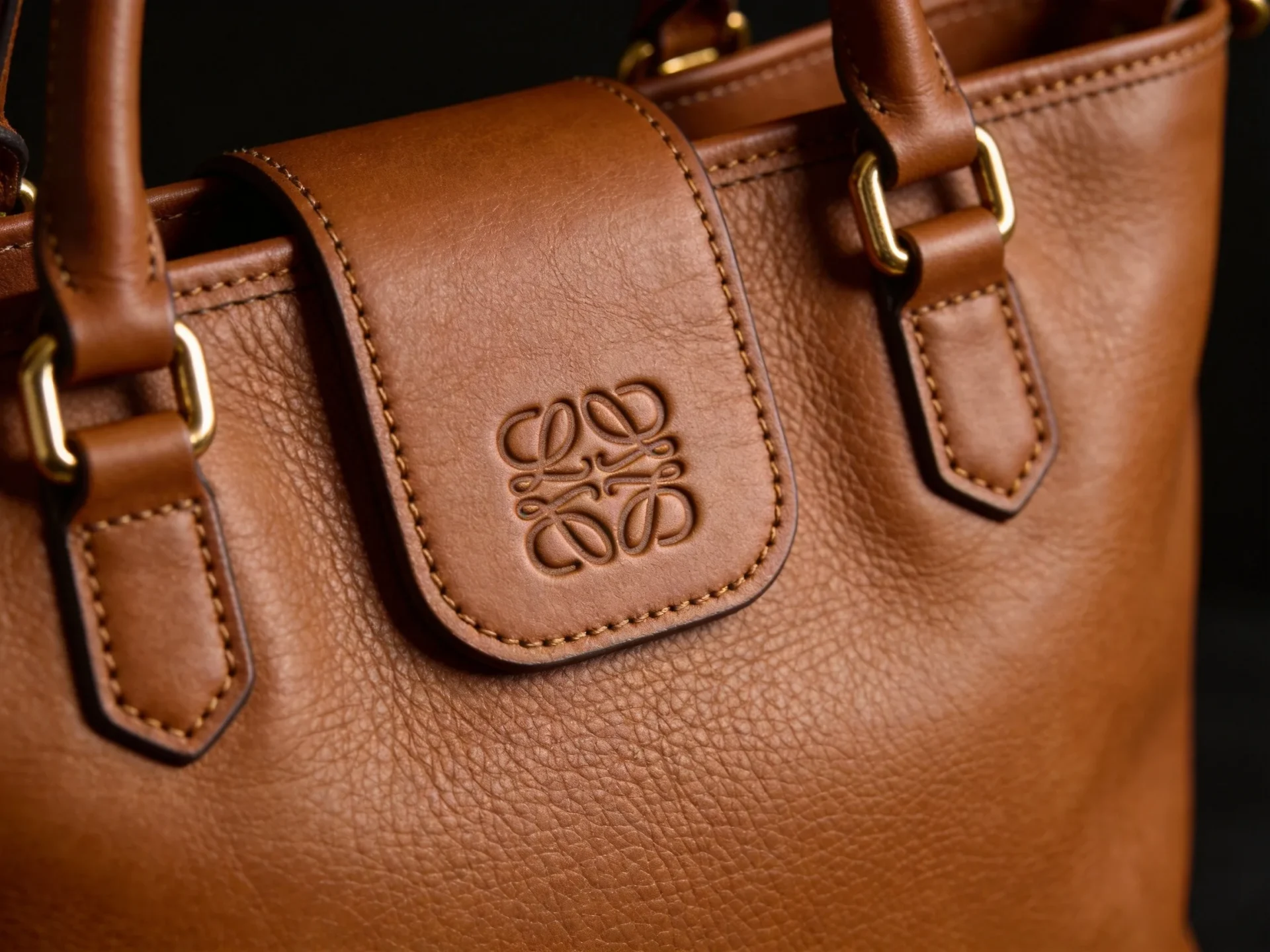 debossed logo detail on a custom leather tote bag with stitched edges