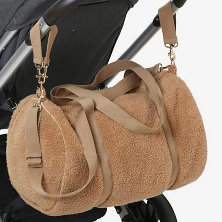 Plush bag hardware close-up showing metal clips, webbing adjuster and bound edge stitching